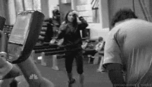a woman is taking a picture of a man on a treadmill in a black and white photo .