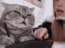 a cat is sitting next to a woman holding a pen and the words a lexine are on the bottom