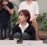 a woman is sitting at a table with her legs crossed while holding a cell phone .