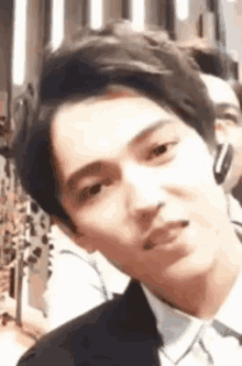 a young man in a suit and tie is looking at the camera .