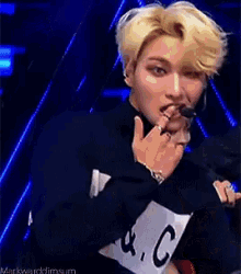 a man with blonde hair is wearing a black jacket with a white tag that says k.c.