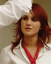 a woman with red hair is wearing a white shirt and a red scarf