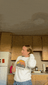 a woman in a kitchen wearing a sweatshirt that says homer stout