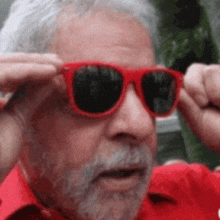 a man with a beard is wearing a pair of red sunglasses .