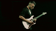 a man in a black shirt is playing a guitar
