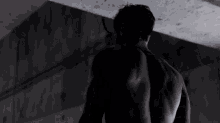 a shirtless man is standing in a dark room