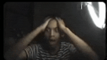 a man in a striped shirt is holding his head in pain