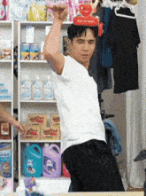 a man in a white shirt is standing in front of a shelf holding a red item that says child my team