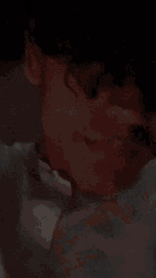 a close up of a person 's face with a blurred background and a white shirt on .