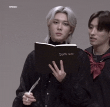 a man is holding a book that says death note on it