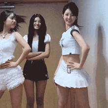 three women are posing for a picture with one wearing a white crop top with the letter a on it