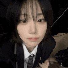 a girl in a school uniform and tie is taking a selfie .