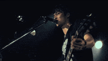 a man singing into a microphone wearing a black shirt with a skull design on it