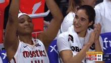 a female basketball player wearing a mystics jersey applauds during a game
