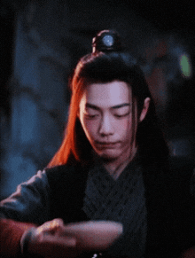 a man with long hair is holding another man 's arm