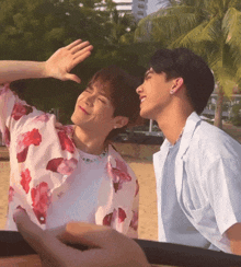 two men are standing next to each other on a beach and one of them is wearing a floral shirt