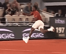 a man in a red shirt and white shorts is jumping in the air on a tennis court