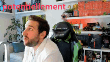a man sits in a green and black gaming chair with the word potentielment written in red behind him