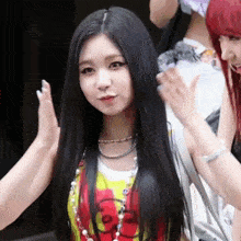 a woman with long black hair is giving a high five while wearing a colorful shirt .