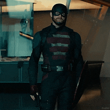 a man in a captain america costume holds a shield and a gun