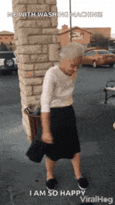 an elderly woman is standing in front of a brick wall holding a purse and dancing .