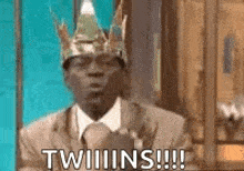 a man in a suit and tie is wearing a crown and says twins .