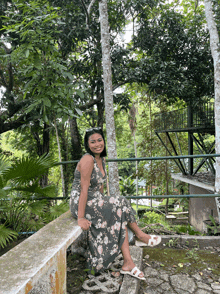 a woman in a floral dress is sitting on a stone bench