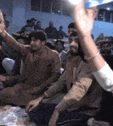a group of people are sitting on the floor with their hands up