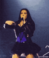 a woman is singing into a microphone with the words edits portirroni behind her
