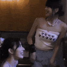 two women are standing next to each other and one is wearing a strapless top with hearts on it