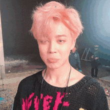 a young man with pink hair is wearing a black sweater with the word velvet on it