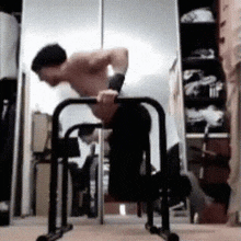 a man is doing push ups on a bar in front of a mirror in a room .