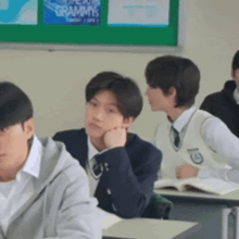 a group of students are sitting at desks in a classroom with a sign that says grammys on it