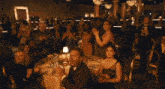 a man in a tuxedo and bow tie sits at a table