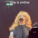 a woman holding a microphone with the words tiny is online written on the bottom