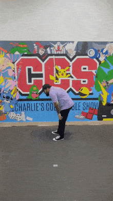 a man is bending down in front of a wall that says css