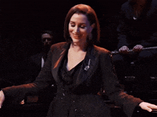 a woman in a black jacket with a brooch that says ' i love you ' on it