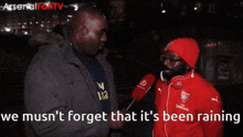 a man in a red arsenal jacket is being interviewed by another man