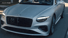 a silver bentley is driving down a street with the words all 's fair on the bottom
