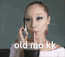 a woman is drinking through a straw while talking on a cell phone with the words old mo kk below her