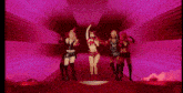 a group of women are dancing on a stage in a pink light .