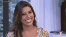 a woman is smiling and looking at the camera while sitting in a room .