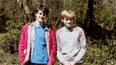 two young men are standing next to each other in a park
