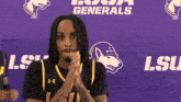 a man clapping in front of a purple banner that says lsu