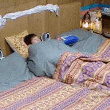 a child is sleeping on a bed with a blanket that has a purple pattern on it