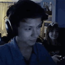 a man wearing headphones is playing a video game with a woman behind him