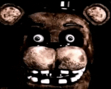 a close up of the face of freddy fazbear from five nights at freddy 's with a black background .