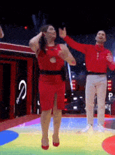 a woman in a red dress is dancing with a man in a red sweater .