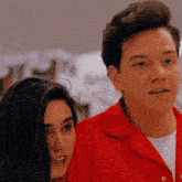 a man in a red shirt stands next to a woman in a white shirt