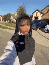 a woman wearing a north face vest takes a selfie in front of a house